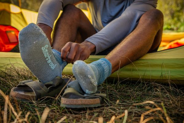 Man putting on his Smartwool socks before getting out of his tent